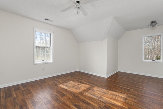 bonus room featuring ceiling fan, lofted ceiling, dark hardwood / wood-style floors, and a textured ceiling