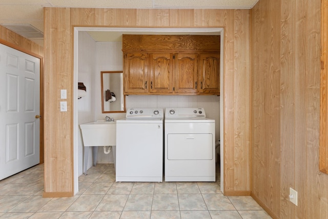 washroom featuring light tile patterned flooring, cabinets, wooden walls, and washer and dryer