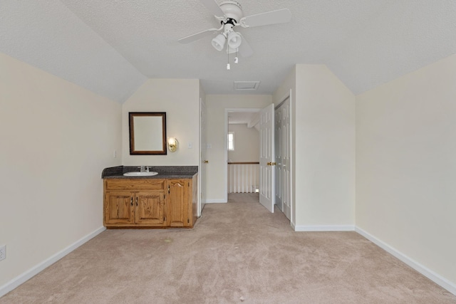 unfurnished bedroom with ceiling fan, sink, light carpet, and a textured ceiling