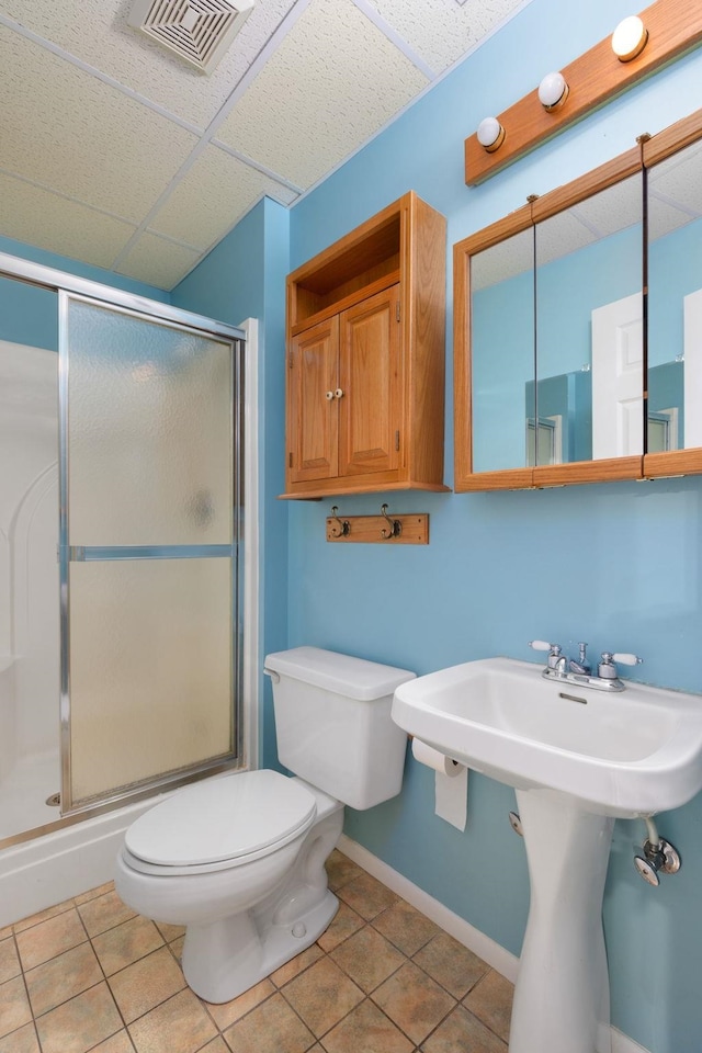 bathroom featuring a shower with shower door, a paneled ceiling, tile patterned floors, and toilet