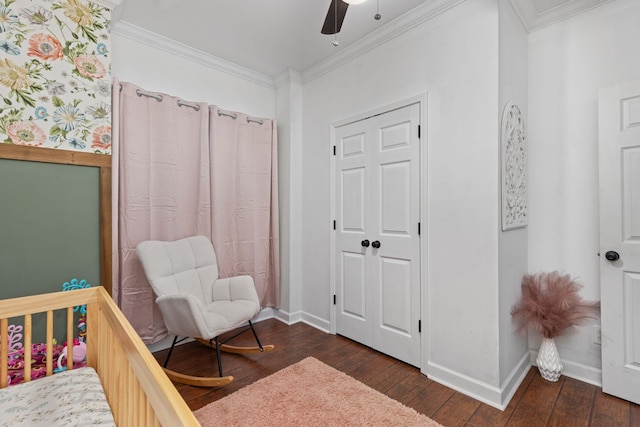 bedroom featuring a crib, dark hardwood / wood-style flooring, ceiling fan, and ornamental molding