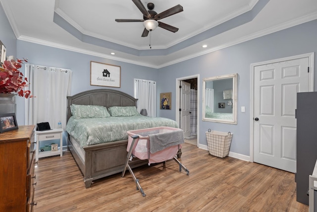 bedroom featuring light hardwood / wood-style flooring, a raised ceiling, ceiling fan, and ornamental molding