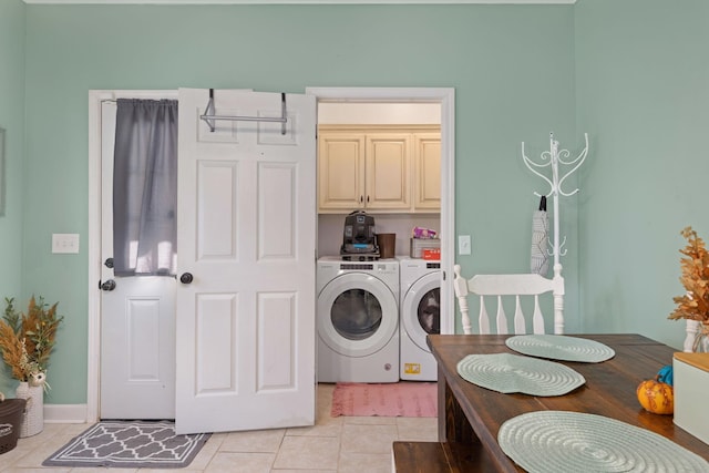 clothes washing area featuring washing machine and clothes dryer, light tile patterned flooring, and cabinets