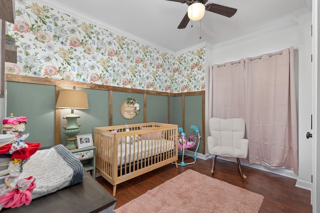 bedroom featuring dark hardwood / wood-style flooring, a nursery area, crown molding, and ceiling fan