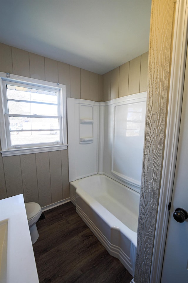 bathroom featuring shower / washtub combination, hardwood / wood-style floors, and toilet