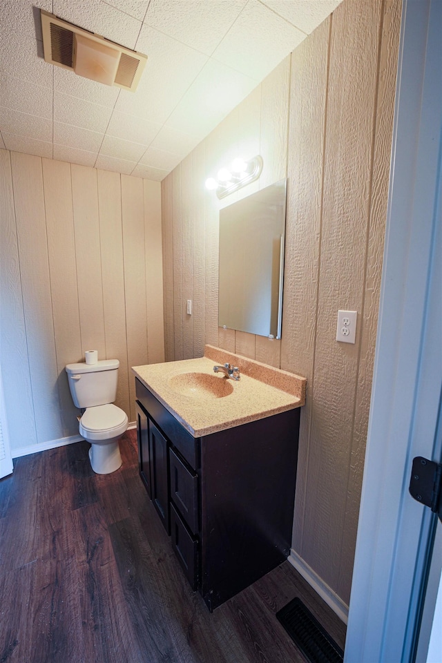 bathroom with vanity, wood-type flooring, toilet, and wood walls