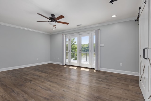 empty room featuring a barn door, ornamental molding, and baseboards