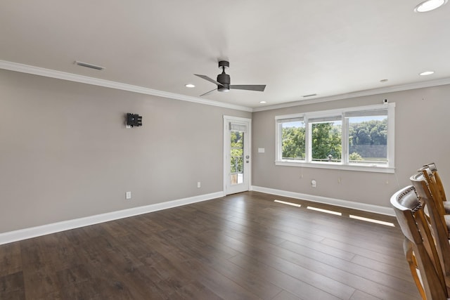 spare room featuring baseboards, visible vents, dark wood-type flooring, and ornamental molding