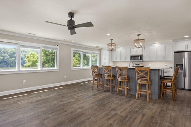 kitchen with white cabinetry, light countertops, appliances with stainless steel finishes, a center island with sink, and pendant lighting