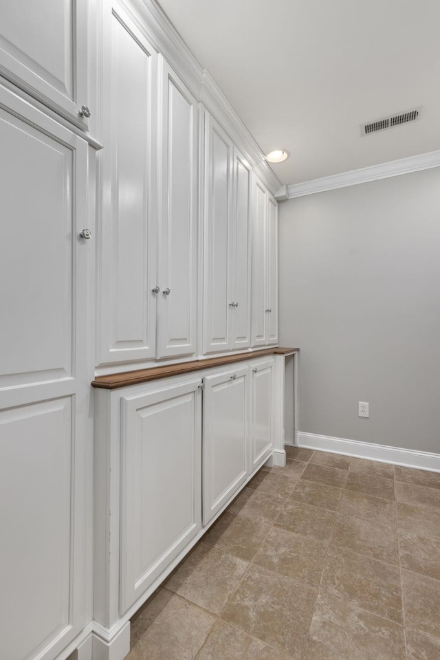 interior space featuring baseboards, visible vents, and ornamental molding