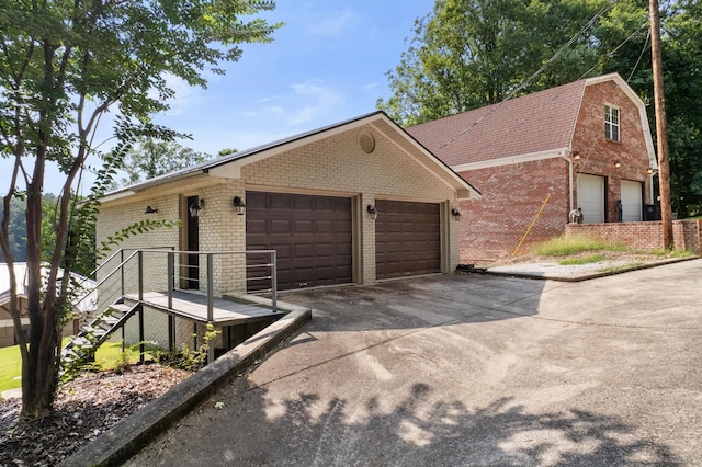 view of front of property with concrete driveway, brick siding, stairway, and a gambrel roof