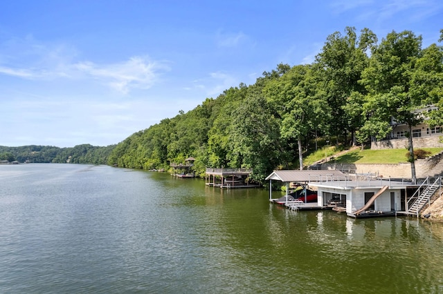 view of dock featuring a water view, boat lift, a forest view, and stairs