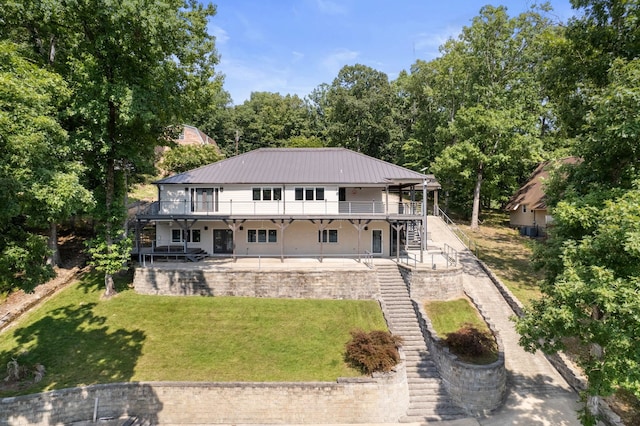 back of property with a lawn, a patio area, metal roof, a wooden deck, and stairs