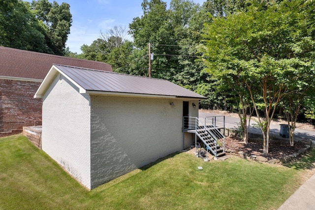 view of property exterior with stairs, a yard, brick siding, and metal roof