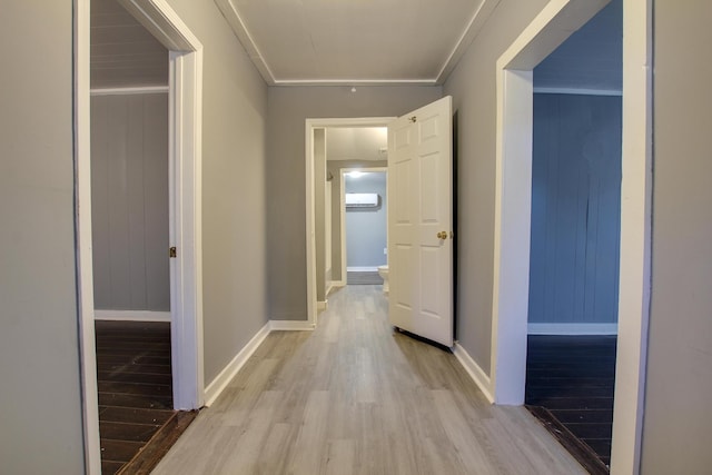 hall with crown molding, a wall unit AC, and light wood-type flooring