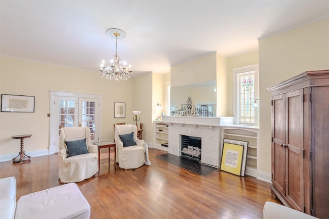 living room with hardwood / wood-style floors, a fireplace, a wealth of natural light, and an inviting chandelier