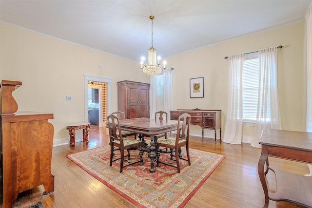 dining area with light wood-type flooring, crown molding, and a chandelier