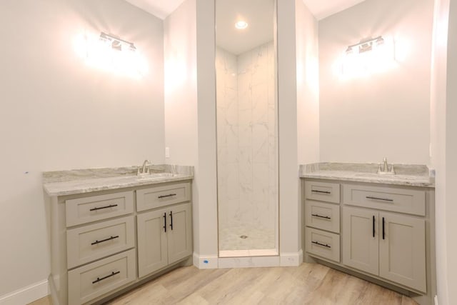 bathroom with hardwood / wood-style flooring, vanity, and tiled shower