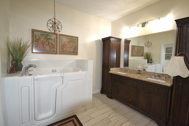 bathroom with a chandelier, vanity, and a tub to relax in