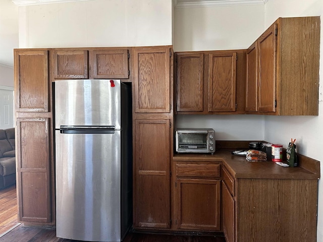 kitchen with stainless steel fridge, dark hardwood / wood-style flooring, and crown molding