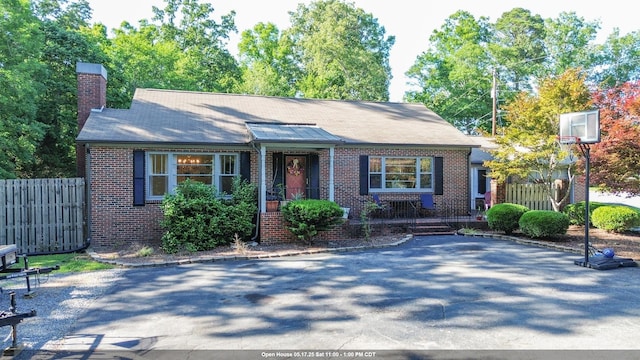  - view of front of house with brick siding, fence, and a chimney