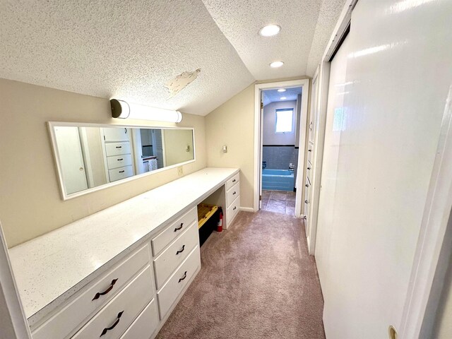 bathroom with lofted ceiling, a textured ceiling, and vanity