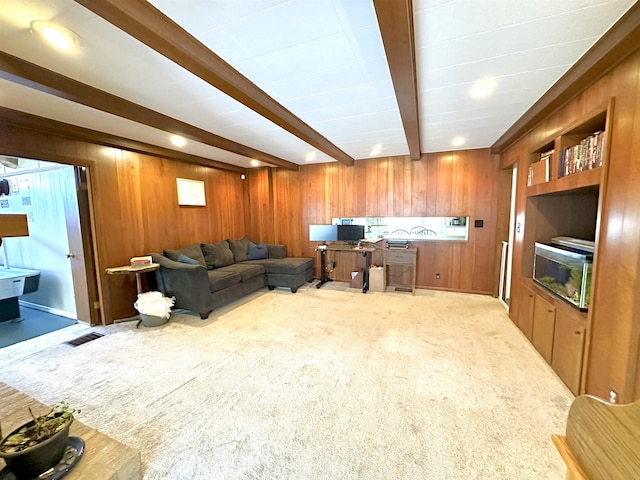 carpeted living room with beamed ceiling and wooden walls