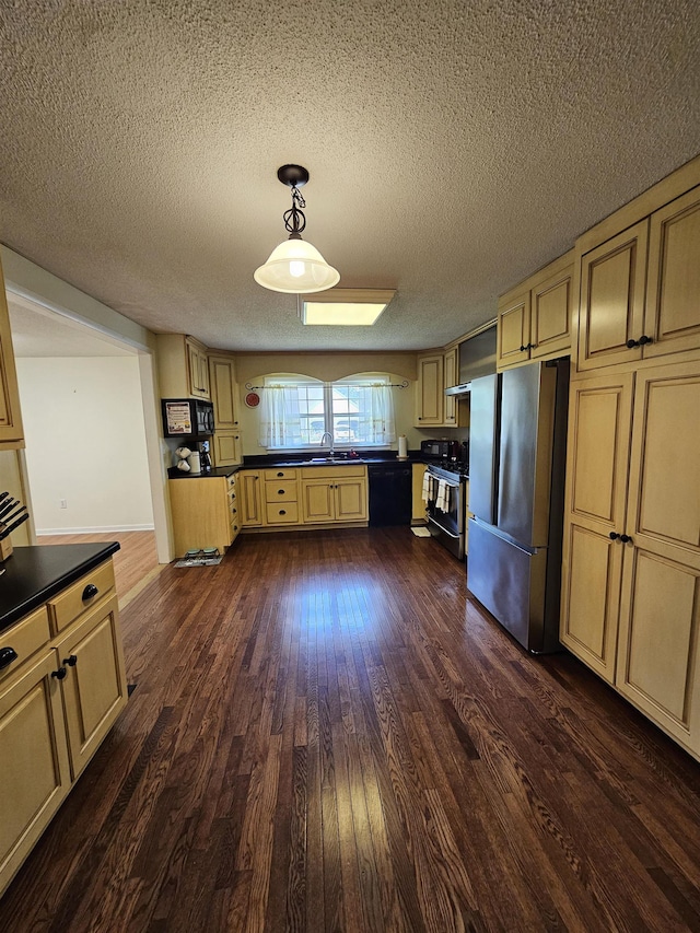  - kitchen with stainless steel appliances, cream cabinets, dark countertops, dark wood-type flooring, and a textured ceiling
