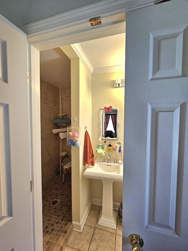  - full bathroom with ornamental molding, tile patterned floors, tiled shower, baseboards, and a sink