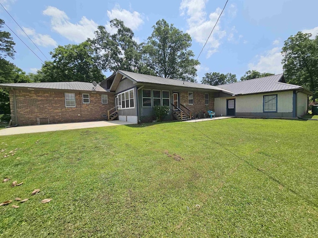  - rear view of property with entry steps, metal roof, a patio area, a yard, and brick siding