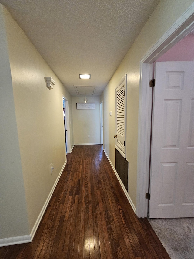  - corridor with wood-type flooring, baseboards, a textured ceiling, and attic access