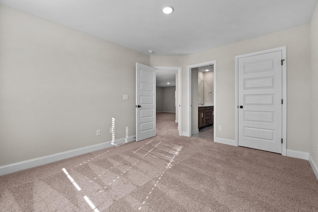 unfurnished bedroom featuring connected bathroom and light colored carpet