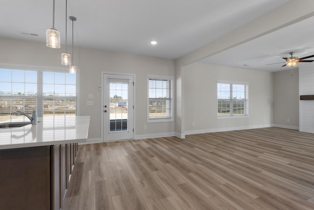 unfurnished living room featuring light hardwood / wood-style floors, ceiling fan, and sink