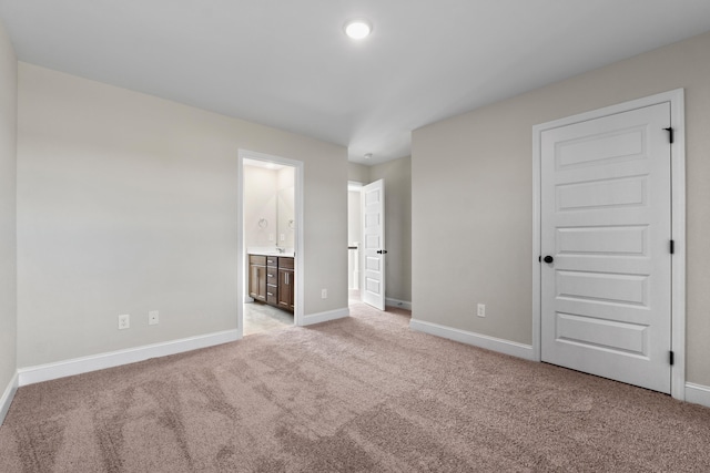 unfurnished bedroom with connected bathroom, light colored carpet, and a closet