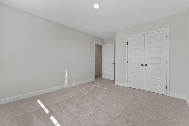 unfurnished bedroom featuring light carpet and a closet