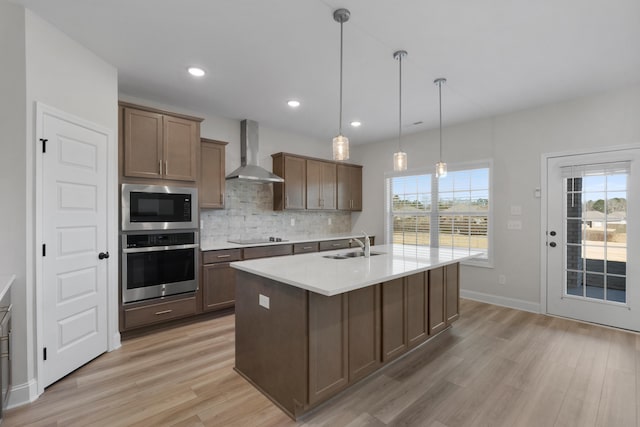 kitchen with black electric stovetop, stainless steel oven, built in microwave, wall chimney range hood, and decorative light fixtures