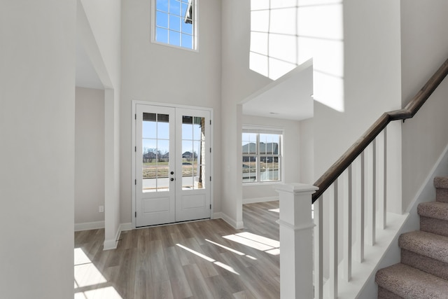 entryway featuring french doors, light hardwood / wood-style flooring, and a high ceiling