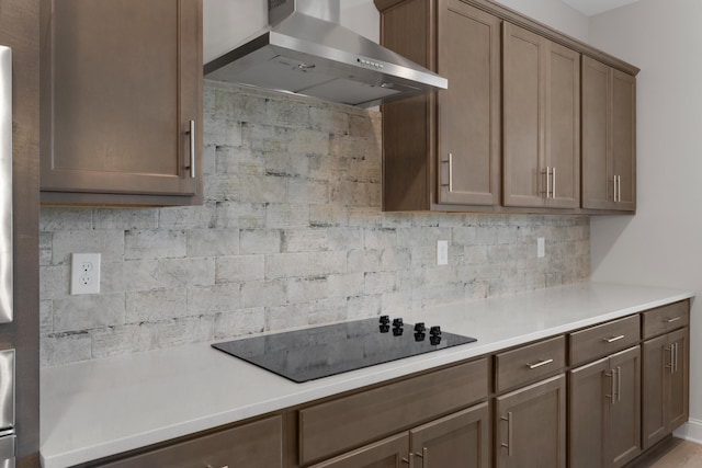 kitchen with black electric stovetop, backsplash, and wall chimney exhaust hood