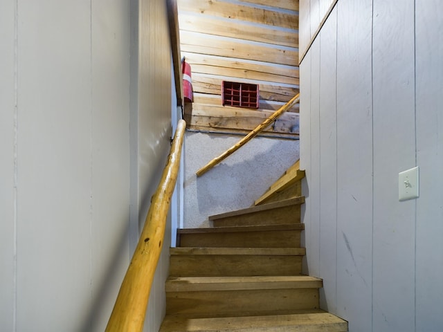 stairway featuring wooden walls