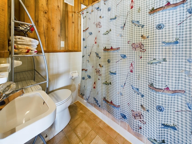 bathroom featuring tile patterned floors, sink, toilet, tile walls, and curtained shower