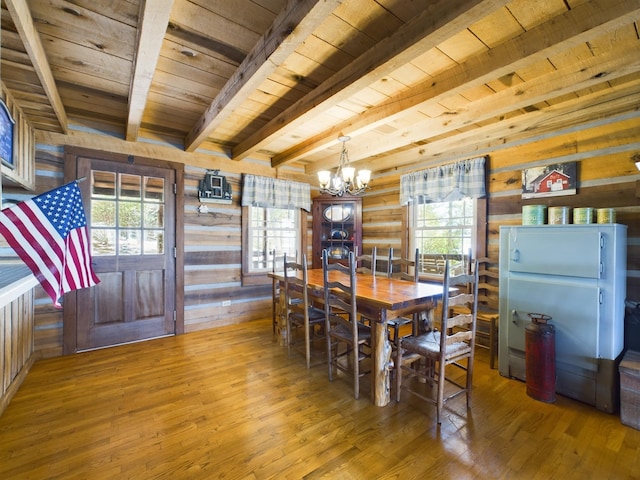 dining area with log walls, wood-type flooring, an inviting chandelier, wooden ceiling, and beamed ceiling