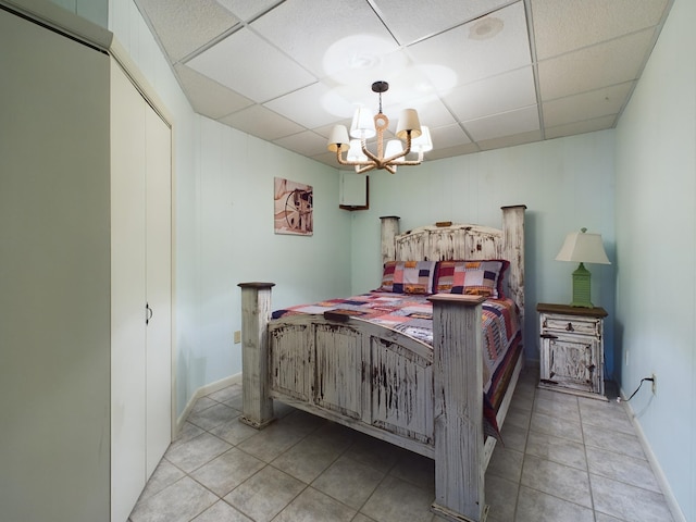 bedroom with a paneled ceiling, a closet, light tile patterned flooring, and a notable chandelier