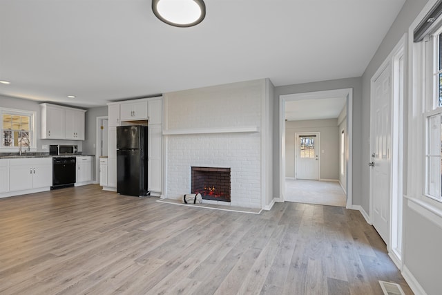 unfurnished living room featuring sink, a fireplace, and light hardwood / wood-style floors