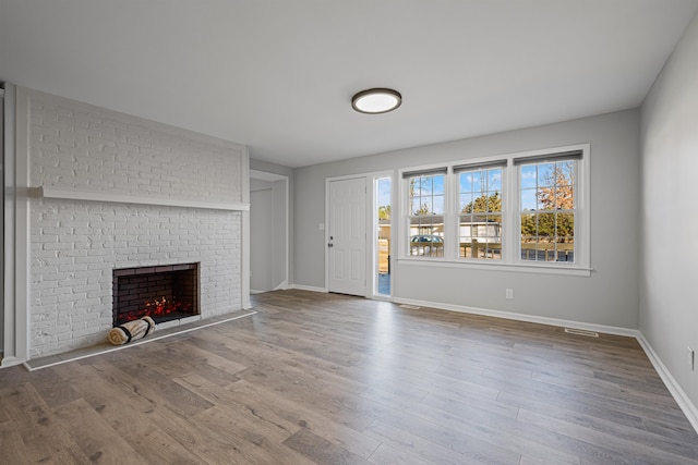 unfurnished living room featuring a brick fireplace and hardwood / wood-style floors