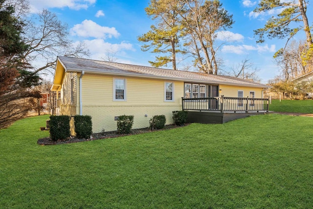 rear view of house with a wooden deck and a lawn