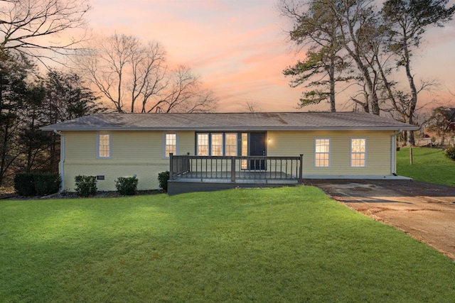 ranch-style home with a deck and a lawn