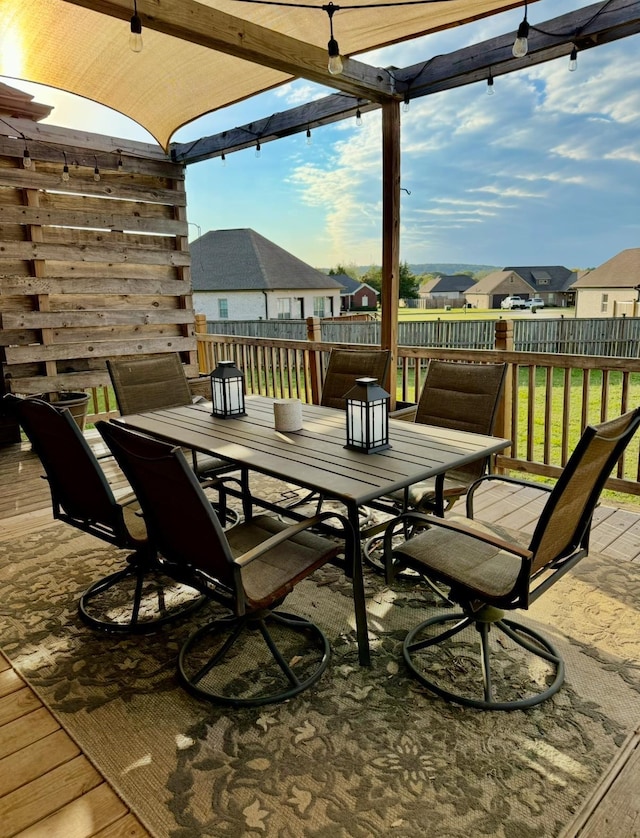 view of patio featuring a wooden deck, outdoor dining space, a fenced backyard, and a residential view