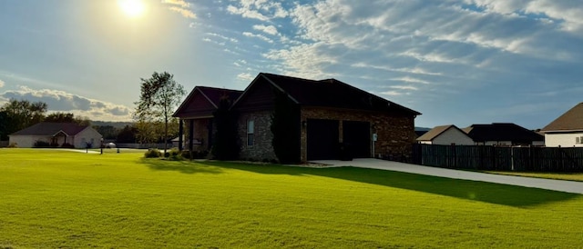 rear view of house featuring a garage, stone siding, fence, and a lawn