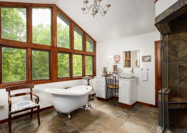  - full bath featuring lofted ceiling, vanity, a freestanding tub, a stall shower, and a chandelier
