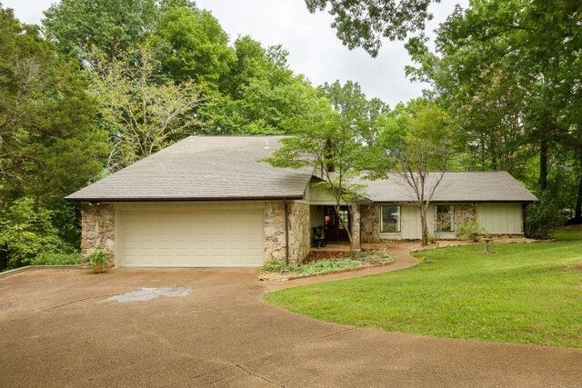  - view of front of house featuring concrete driveway, a garage, a front yard, and stone siding